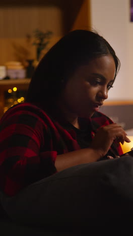 woman using smartphone at night on a couch