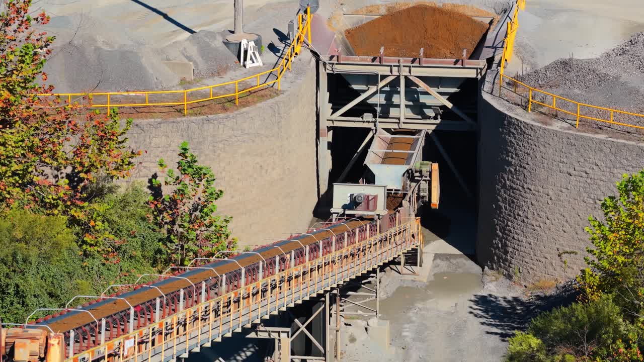 Industrial conveyor machinery above gravel processing equipment at quarry