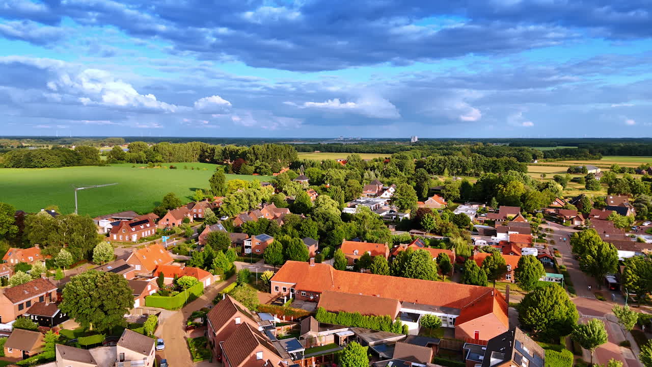 Grønt, solfylt landskap av en vakker by i Nederland. Store, luftige skyer på himmelen over. Flyfoto.