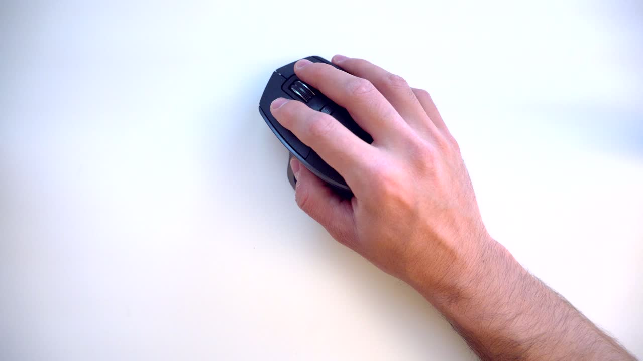 hombre moviéndose y haciendo clic con el mouse de una computadora sobre una mesa blanca