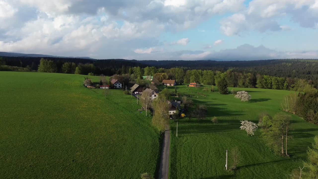 Utsikt over noen hus blant engene nær skogen.