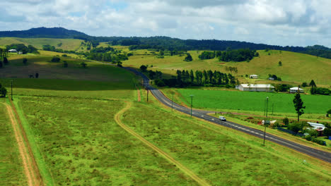 country road passing through green fields in atherton tablelands, queensland, australia - aerial drone shot