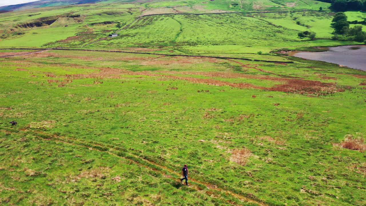 vista aérea de un hombre caminando por un sendero en el campo, día soleado