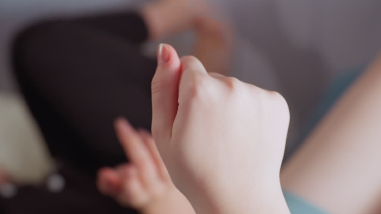 Close up of relaxed female hand mid gesture with natural lighting and soft blurred background showing resting body and legs on sofa, conveying calmness, casual interaction