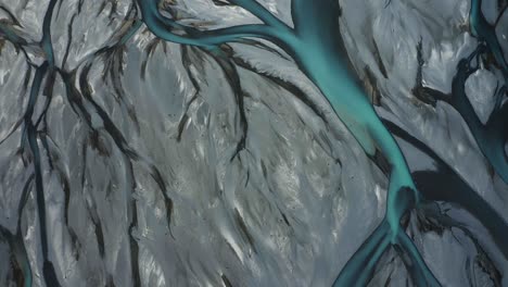 top down drone shot of blue glacial braided river flowing like veins through gray landscape, tasman river, new zealand, south island