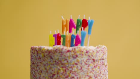 foto de estudio de pastel de cumpleaños giratorio cubierto con decoraciones y velas que deletrean feliz cumpleaños 2