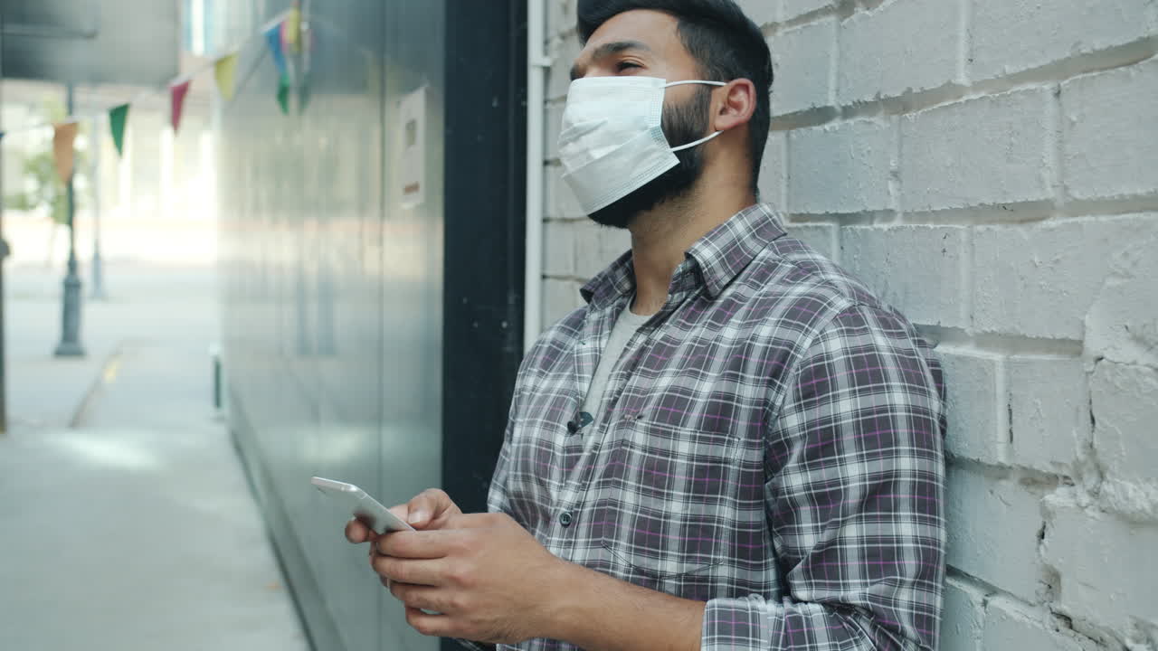 Man using phone outdoors while wearing a mask during Covid-19 pandemic.