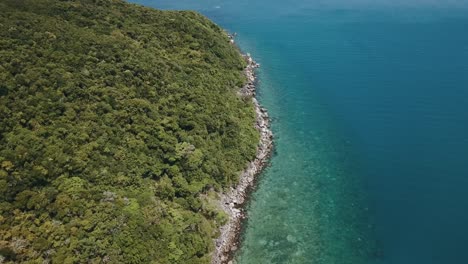 Drone-aerial-pans-up-to-show-a-tropical-island-with-clear-blue-water-and-sandy-beaches-on-the-Great-Barrier-Reef