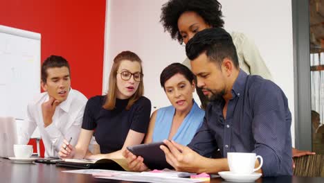 grupo de ejecutivos discutiendo sobre una tableta digital en la sala de conferencias