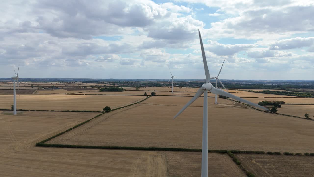 Scenic aerial drone view of countryside farmland with tall wind turbines producing renewable power near Burton Latimer England