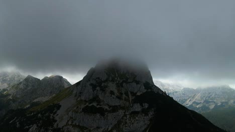 drone footage of a big mountain in fog and mist drone moving backward and filmed in 4k filmed in slovenian mountain in the alps in beautiful cloudy weather