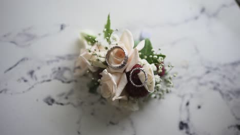 macro shot of two wedding rings on small bouquet flowers placed on a ceramic table