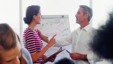 Business-executives-discussing-over-flip-chart-during-meeting-4k