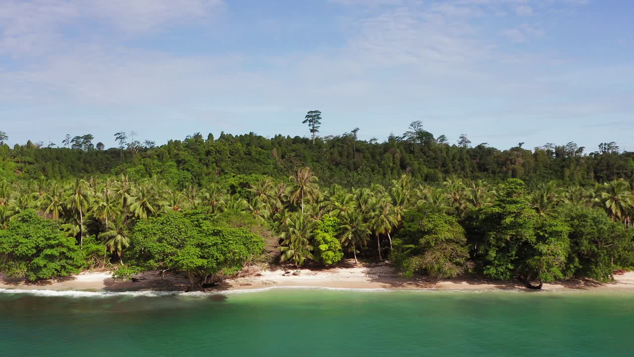 Aerial backwards flight of tropical Indonesian palm beach with green water