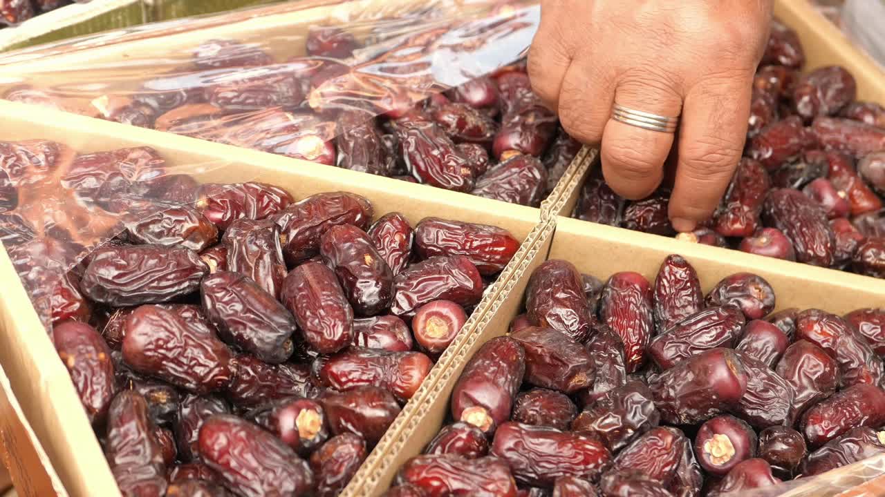 Hand picking Dates from a Box in a Market