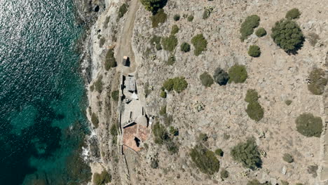 vista aérea mirando hacia abajo sobre la casa de piedra rústica en los acantilados de cap de creus del parque nacional ladera rocosa de la montaña y agua esmeralda brillante