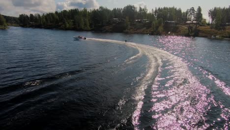 slowmotion of drone flying over a young man riding a wakeboard after a sport boat in the swedish archipelago in the summer sub4
