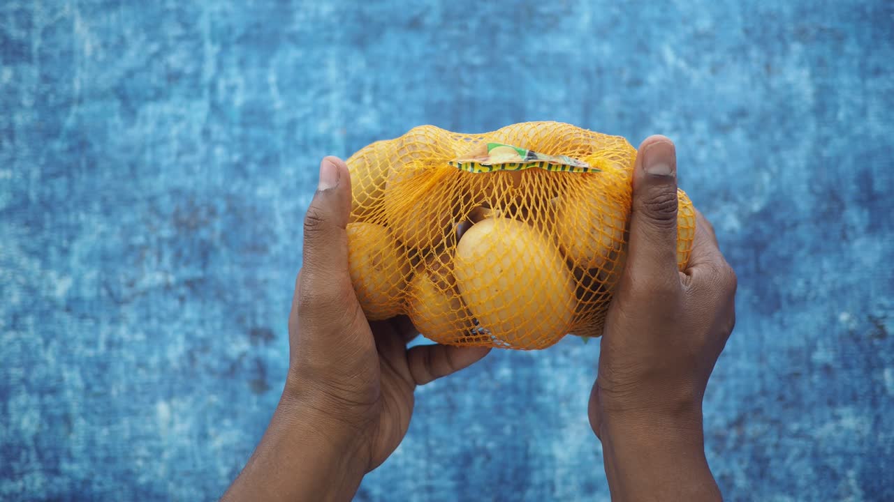 Hands holding a mesh bag of fresh potatoes