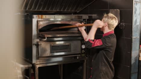 chef poniendo pizza en un horno a leña