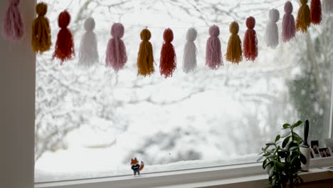 decorated window during snowfall outdoors in winter