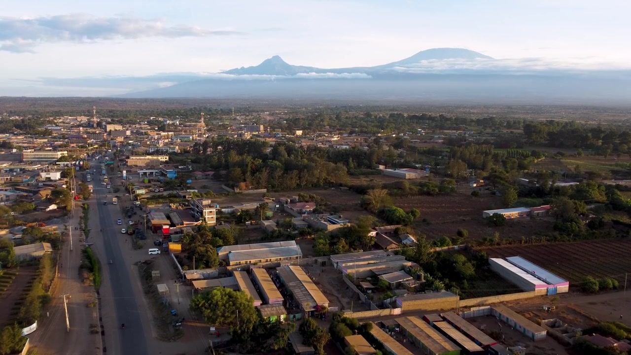 Riprese cinematografiche con drone della città di Kimana che risplende nella luce della sera con le cime innevate del Monte Kilimanjaro che si ergono sullo sfondo. La vivace città di passaggio si trova vicino al Parco Nazionale di Amboseli.