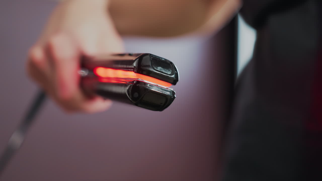 Inspección minuciosa de una plancha caliente, toma de estudio centrada en los detalles de la plancha, imagen que muestra una vista detallada de un estilista que analiza un dispositivo de alisado brillante en un entorno de estudio