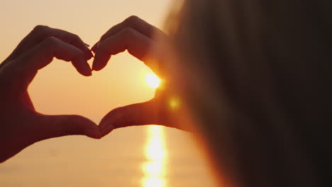 A-Woman-Hands-Shows-A-Heart-Symbol-Over-The-Sea-Where-The-Sun-Rises-Above-The-Rose-Water-Love-And-Ho