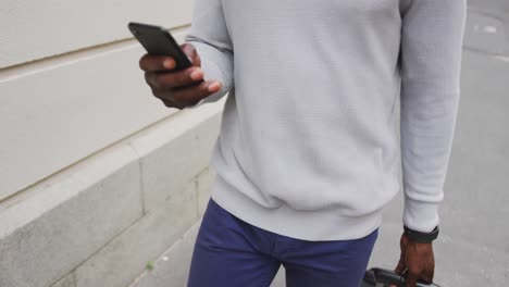 african american man walking in the street and using his phone