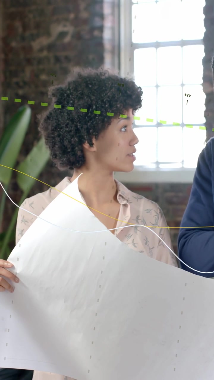Video verticale: Donna che tiene in mano un progetto e parla, uomo che porge una penna mentre linee in sovrimpressione mostrano il design