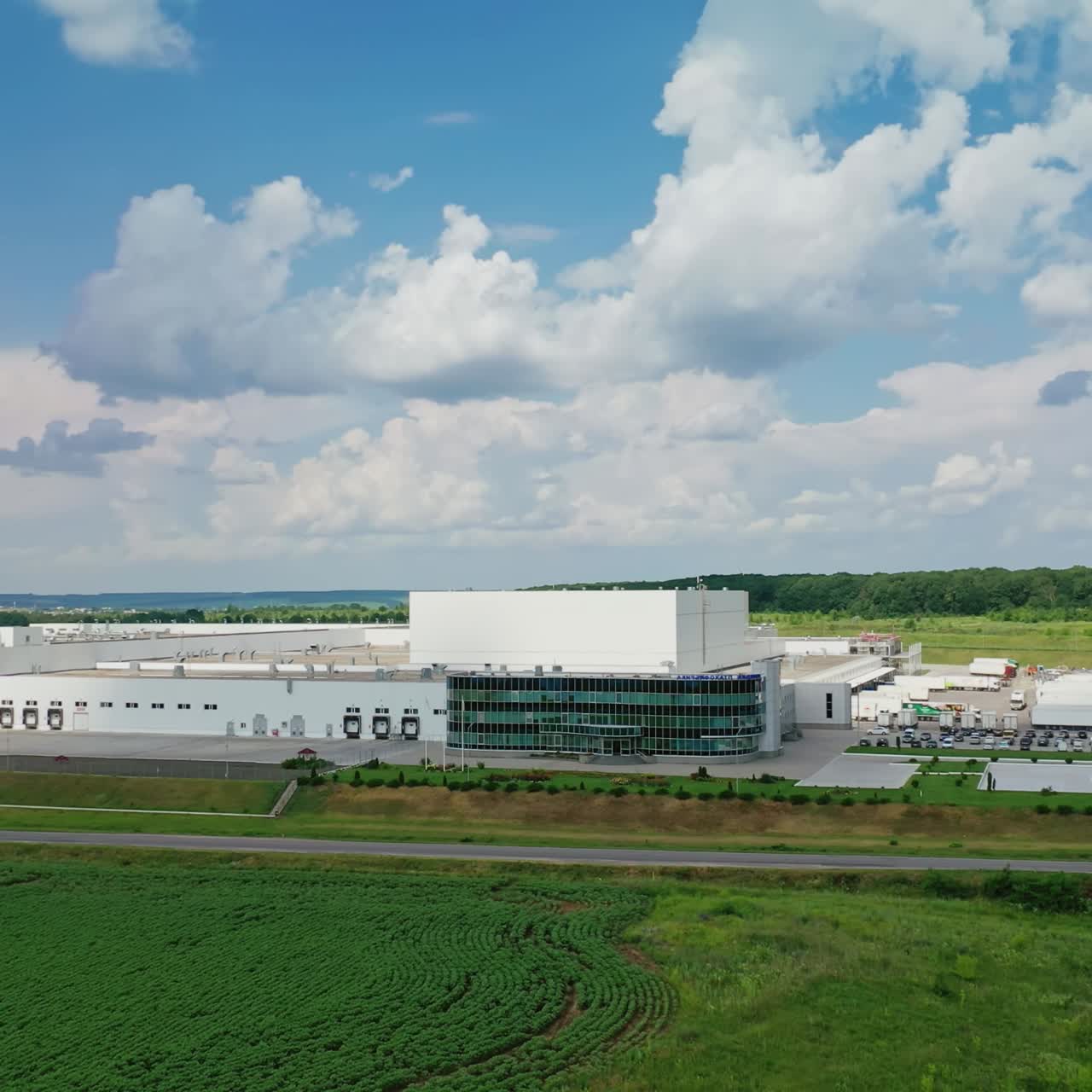 Industrial area among natural environment. Huge territory of manufacturing complex on green field under beautiful summer sky. Front view.