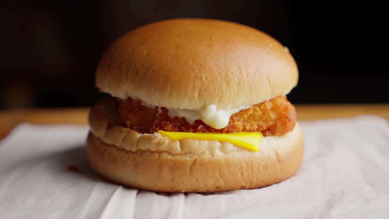 Primo piano su un invitante hamburger di pesce fritto con maionese e formaggio.
