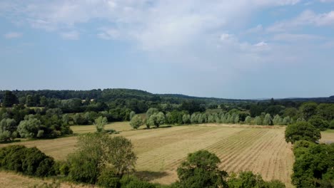 Drone-shot-flying-over-a-farm-and-fields-in-Wilton,-England-in-summer