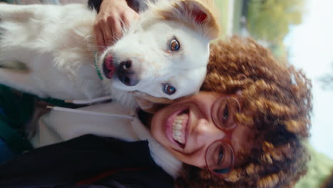 young woman hugging dog and making video call outdoors