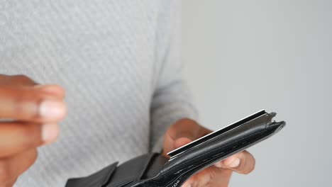 a man's hand holding a credit card and wallet.