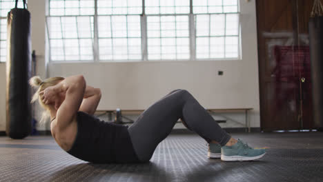 vista lateral de una mujer caucásica en forma realizando abdominales en el gimnasio