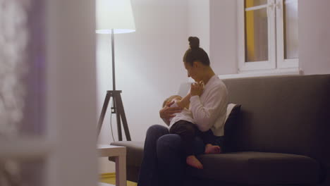 Young-Mother-Breastfeeding-Her-Baby-Boy-While-Sitting-On-The-Sofa-In-The-Living-Room-At-Home-1