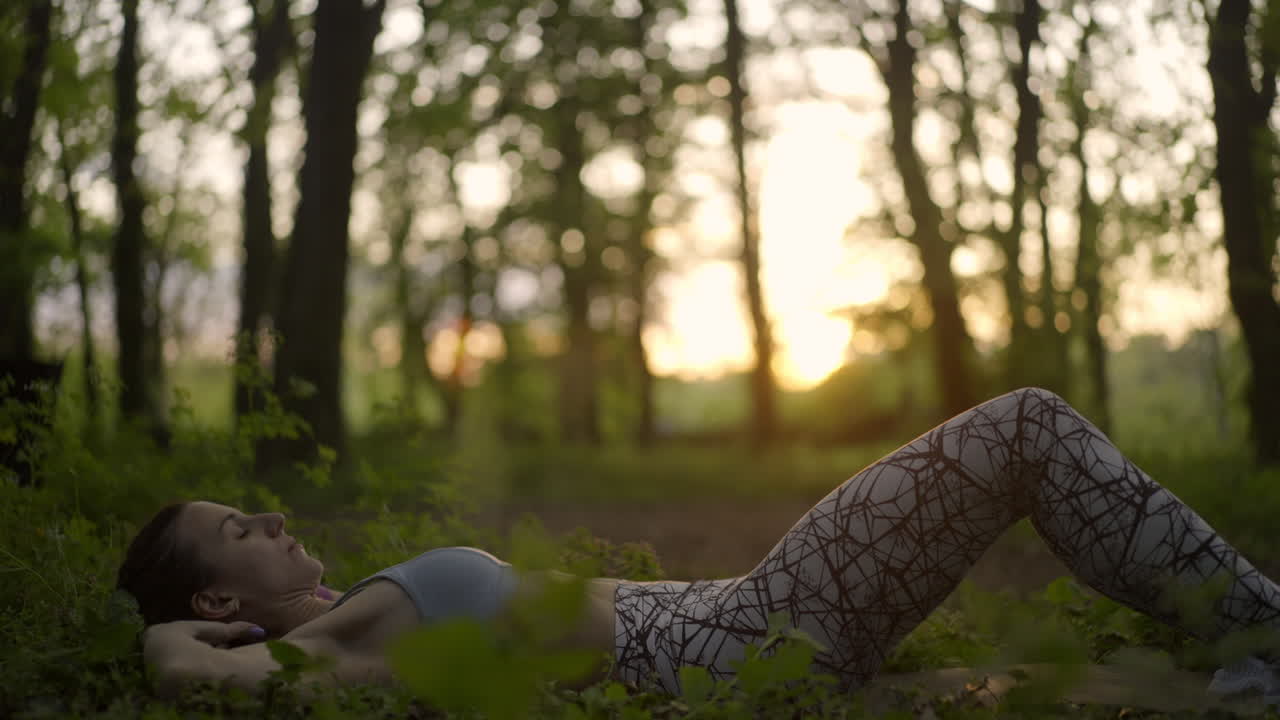 Frau macht Sit-ups im Wald bei Sonnenaufgang