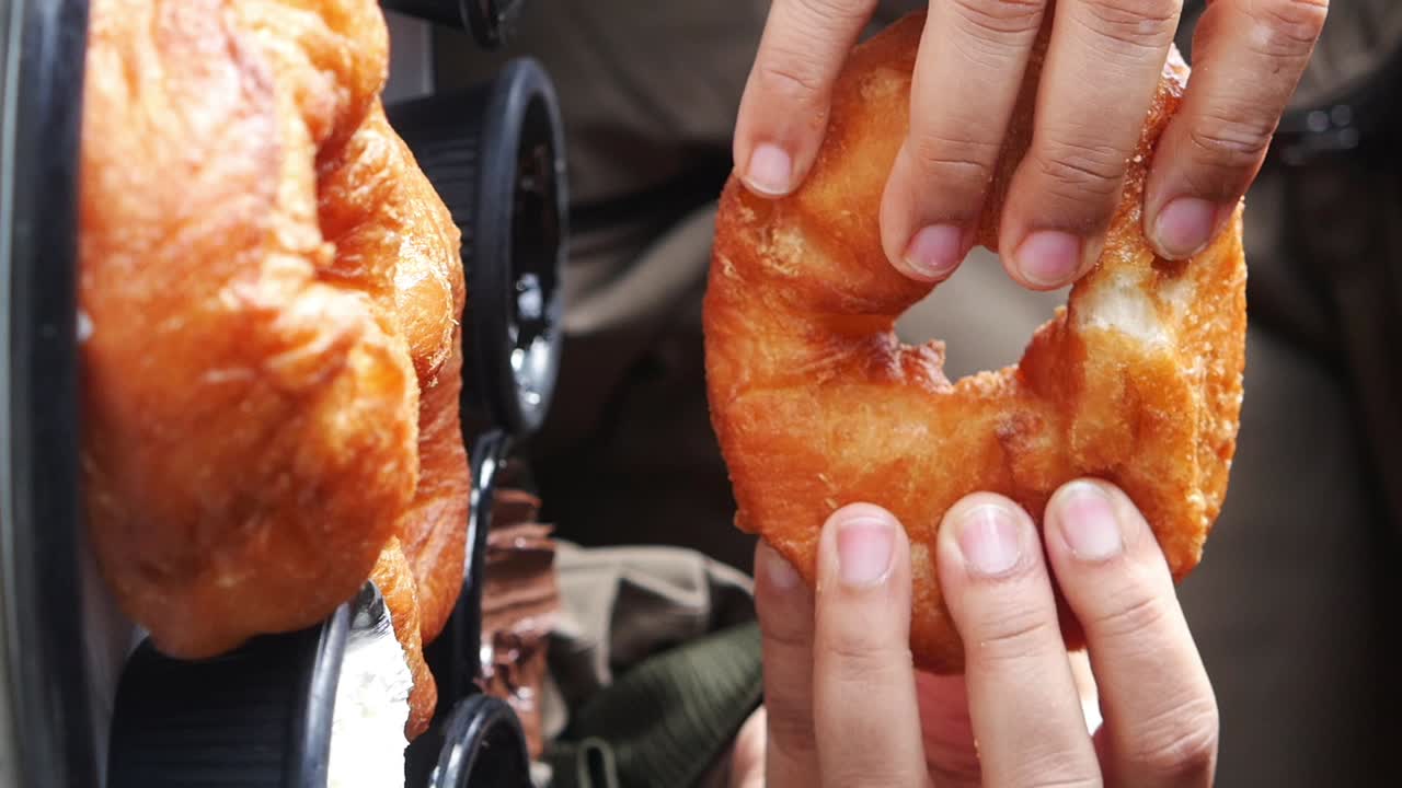 Close-up of Hands Holding and Eating a Freshly Fried Doughnut