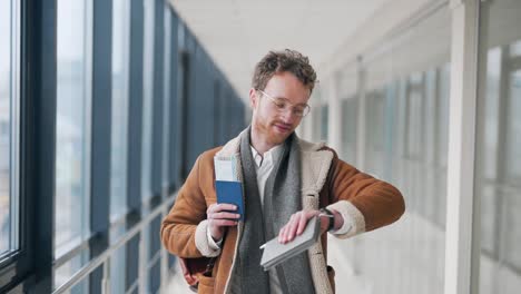 un bell'uomo alla moda con un biglietto e un passaporto cammina lungo il corridoio