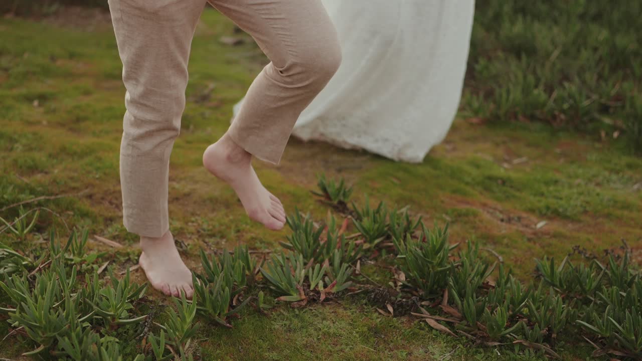 Bare feet walking on grass beside wedding dress outdoors