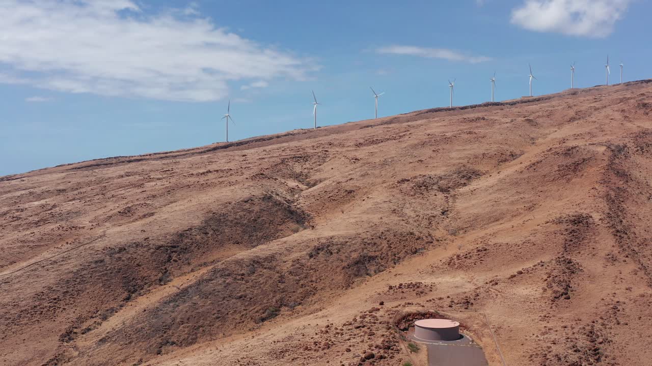 Wide panning aerial shot of the Kaheawa Wind Farm along the coast of West Maui in Hawai'i