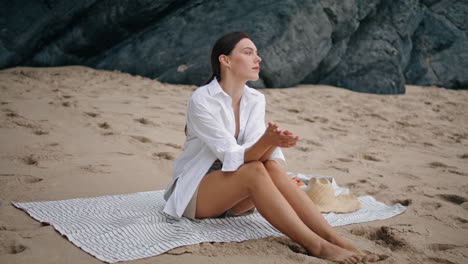 woman sitting blanket beach looking seascape. girl relaxing at coverlet vertical