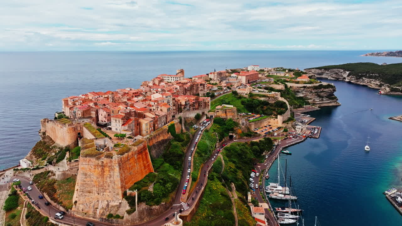 Aerial drone shot over the historic coastal town of Bonifacio in Corsica, France. High view of the rocky steep cliff and the turquoise sea. Ancient Citadel overlooking the rugged coastline