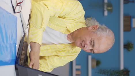 Vertical-video-of-Home-office-worker-old-man-smiles-at-camera.