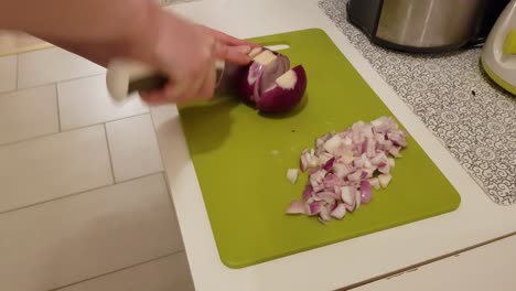 mujer caucásica cocinando y cortando cebolla morada