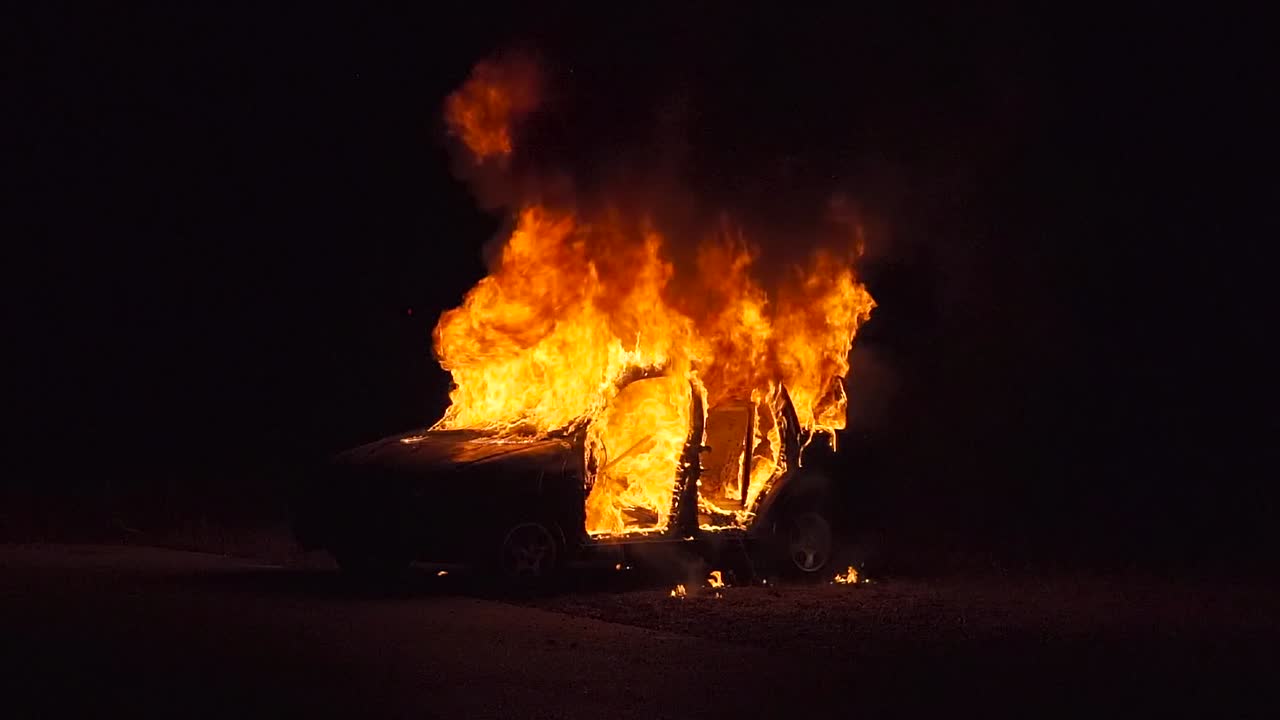 burning car at night, left side, half diagonal from front, long shot, wide shot