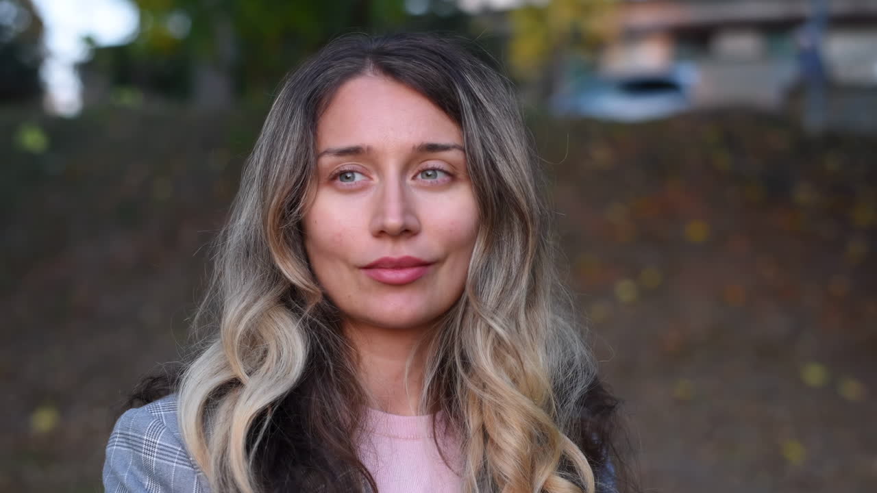 Close up of a blonde woman smiling at the camera in the park