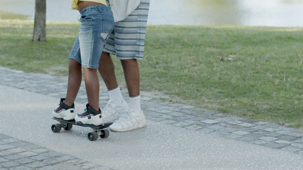 Father teaching son skateboarding, holding him under armpits.