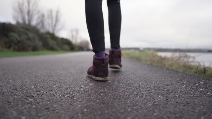 Slow motion, low, close up shot from the back of a girl walking with very shallow depth of field