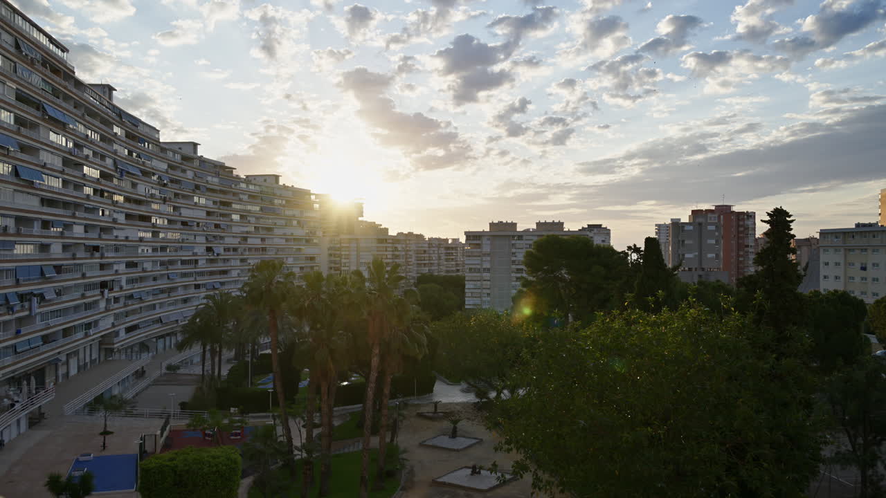 Lapso de tempo de nuvens se movendo sobre prédios de apartamentos e um parque urbano verde em Alicante, Espanha